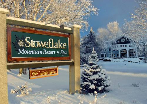 Sign for Stoweflake Mountain Resort & Spa in a snowy landscape, with a cozy lodge visible in the background.