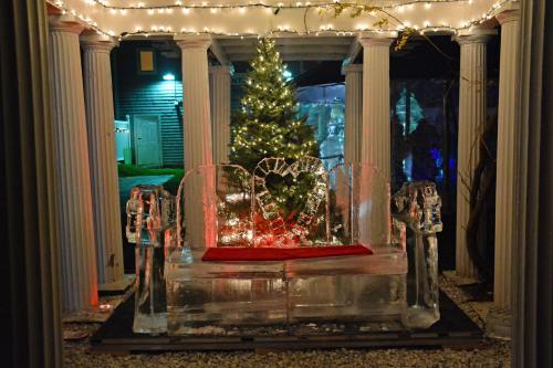 An ice bench with horse sculptures, surrounded by festive lights and a decorated Christmas tree.