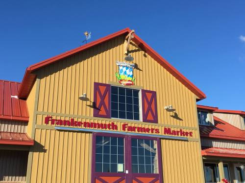 Frankenmuth Farmers Market building with a colorful sign and a blue sky in the background.