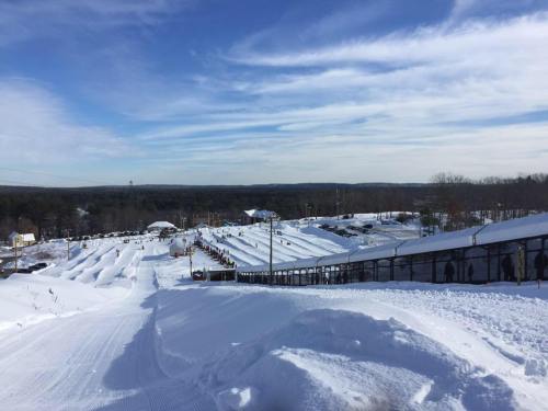 A snowy landscape with a tubing hill and people enjoying winter activities under a clear blue sky.