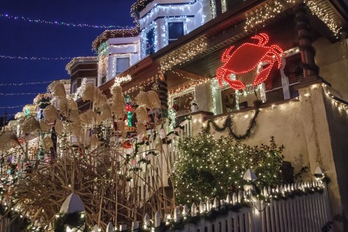 A festive house decorated with colorful lights, featuring a large red crab sign and holiday decorations.