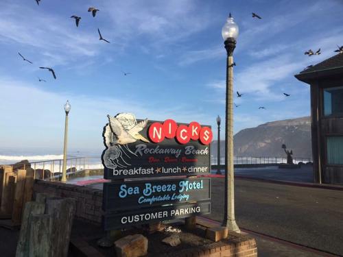 Sign for Nick's Rockaway Beach with a view of the ocean, birds flying, and nearby Sea Breeze Motel.