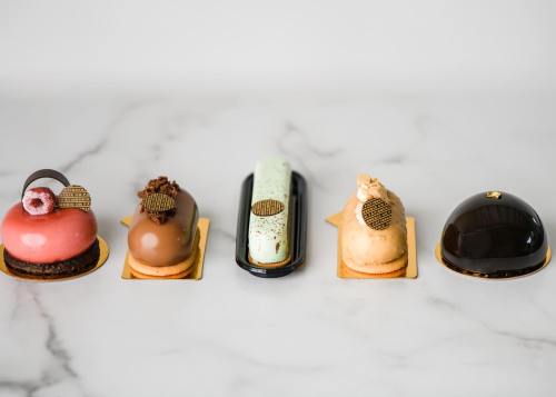 Five elegant pastries in various colors and shapes, displayed on a marble surface.