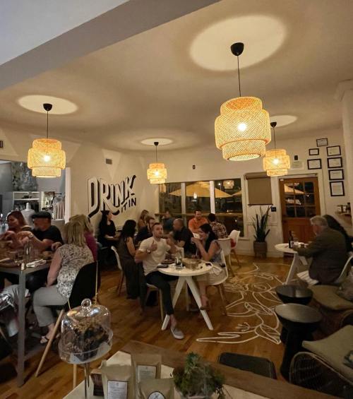 A cozy restaurant interior with diners at tables, warm lighting, and a modern decor featuring a large wall sign.