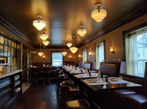 A cozy restaurant interior with vintage lighting, wooden tables, and booths, creating an inviting atmosphere.