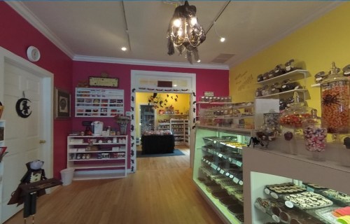 Brightly colored candy shop interior with shelves of sweets, a glass display case, and decorative elements.