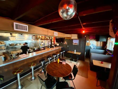 A cozy restaurant interior with a bar, tables, and a disco ball hanging from the ceiling. Warm lighting creates a welcoming atmosphere.