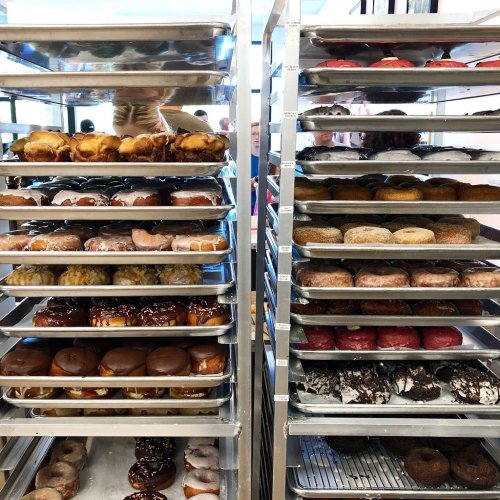 A display of various donuts on metal racks, featuring glazed, chocolate, and frosted varieties.