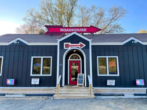 A black and red building with a sign reading "Roadhouse" and an arrow, surrounded by trees.