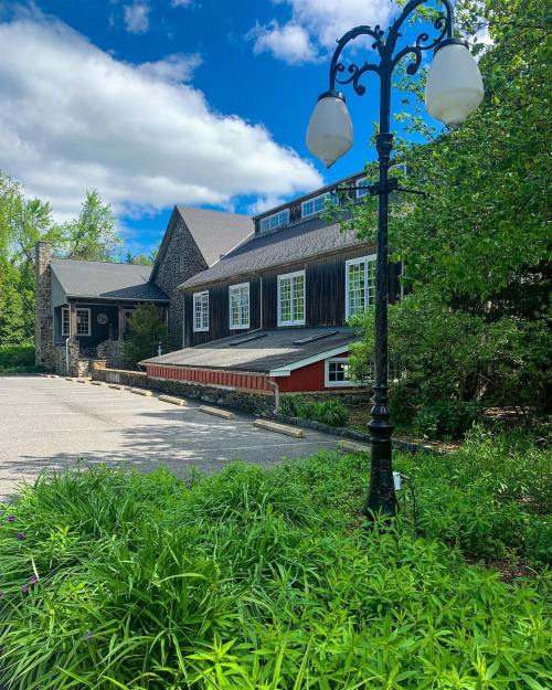 A charming building with a mix of stone and wood, surrounded by lush greenery and a vintage street lamp.