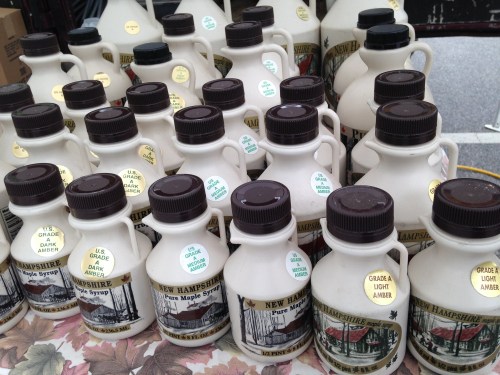 A display of various bottles of New Hampshire pure maple syrup in different grades and colors.