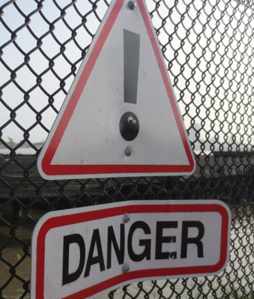 A warning sign with an exclamation mark and the word "DANGER" on a chain-link fence.