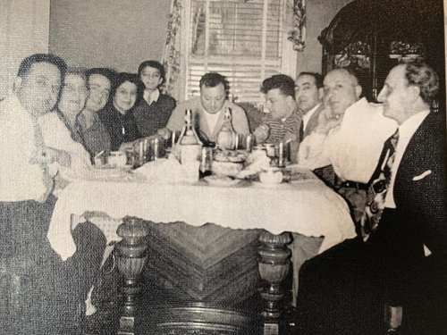A group of people gathered around a dining table, enjoying a meal together in a cozy setting.