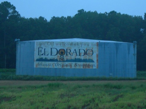 A large metal tank with a faded sign reading "Lion Oil welcomes you to El Dorado, Arkansas: Original Boomtown."
