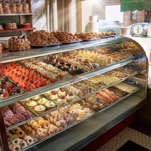 A display case filled with a variety of colorful pastries, cookies, and desserts in a bakery.