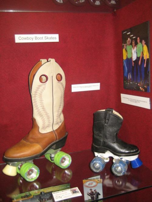 Display of cowboy boot skates: one brown and one black, mounted on colorful roller skate wheels.