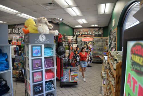 A woman walks through a colorful gift shop filled with merchandise, including plush toys and clothing displays.