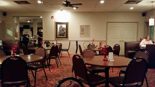 A dimly lit restaurant with empty tables, red decorations, and staff preparing in the background.