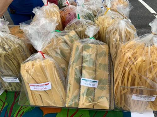 A variety of packaged pasta in clear bags displayed on a table at a market.