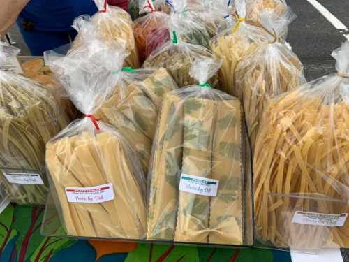 A variety of packaged pasta in clear bags displayed on a table at a market.