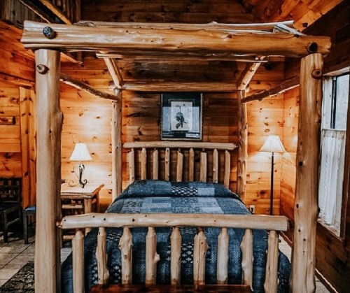 Cozy wooden cabin bedroom featuring a four-poster bed, warm lighting, and rustic decor.