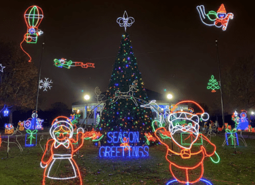 Colorful holiday lights decorate a Christmas tree, with festive characters and "Season's Greetings" sign in the foreground.