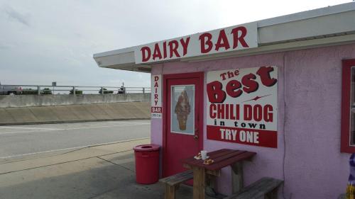 A colorful dairy bar with a sign advertising "The Best Chili Dog in town" and an ice cream cone on display.