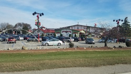 A busy parking lot in front of a festive building decorated for the holidays, with trees and ornaments visible.
