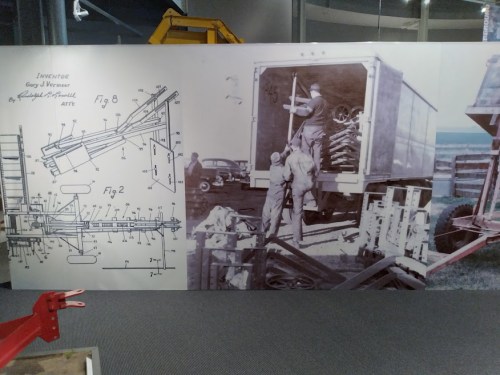A display featuring a vintage patent drawing and historical photo of workers loading equipment onto a truck.