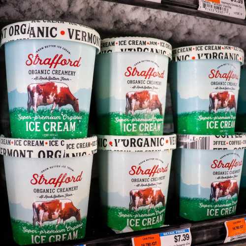 Six tubs of Strafford organic ice cream on a store shelf, featuring a cow and Vermont landscape design.