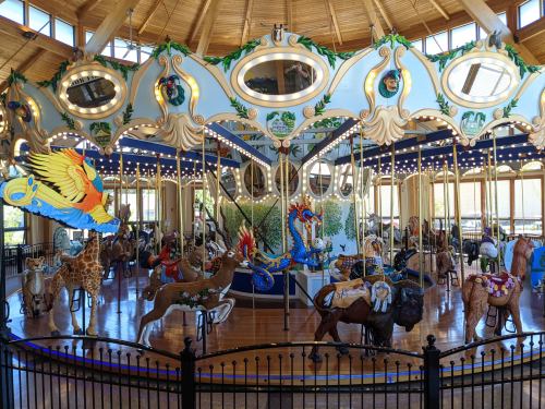 A colorful carousel featuring various animal figures, including a giraffe and a dragon, under a wooden ceiling.