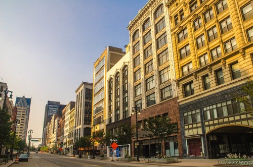 A city street lined with historic and modern buildings under a clear blue sky.