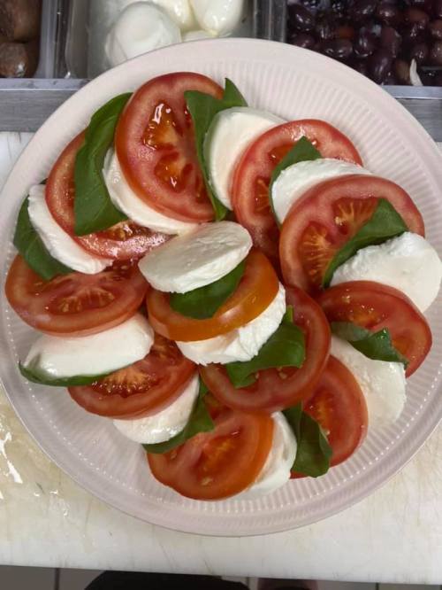 A plate of caprese salad featuring layers of fresh mozzarella, tomatoes, and basil leaves.