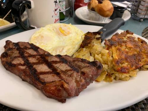 A plate featuring a grilled steak, two fried eggs, and a serving of hash browns.