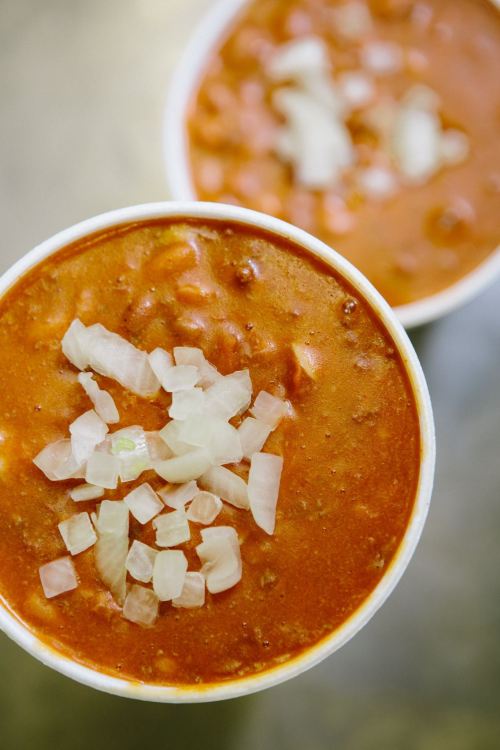 Two bowls of chili topped with diced onions, showcasing a rich, hearty texture and vibrant red color.