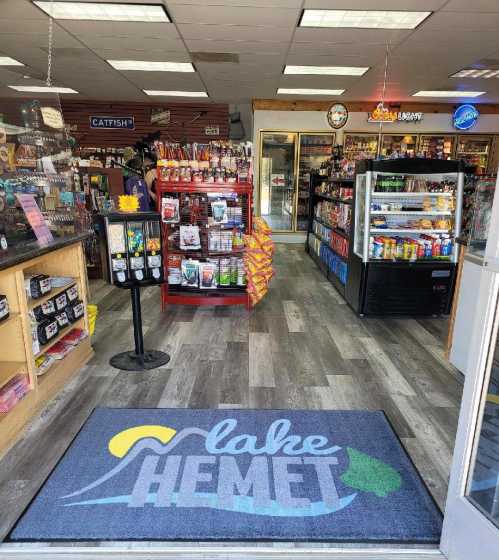 Entrance of a store with a welcome mat reading "Lake Hemet," showcasing snacks and drinks inside.