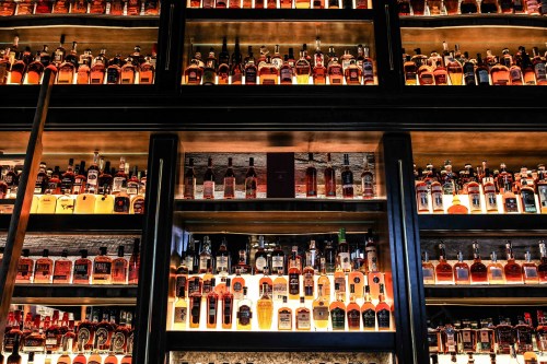 A well-organized display of various whiskey bottles on shelves, showcasing a range of colors and labels.