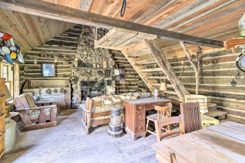 Cozy rustic cabin interior with wooden beams, a stone fireplace, and vintage furniture. Warm and inviting atmosphere.
