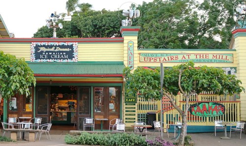 Colorful storefront of a Hawaiian ice cream shop with outdoor seating and lush greenery.