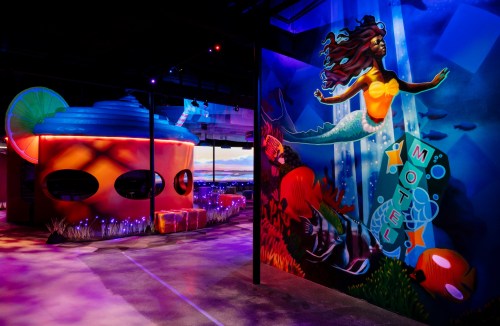Colorful mural of a mermaid and vibrant motel structure in a whimsical, underwater-themed space.