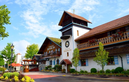 A charming, rustic inn with a tower, colorful flowers, and a blue sky in the background.