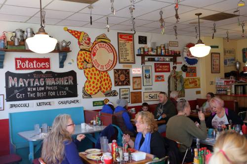 A cozy diner with colorful vintage decor, patrons enjoying meals at tables, and a lively atmosphere.
