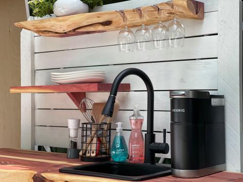A modern kitchen setup featuring a Keurig coffee maker, dishware, and cleaning supplies on wooden shelves.