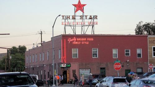 A restaurant with a neon sign reading "The Star" and "Family Style" in a bustling street scene at dusk.