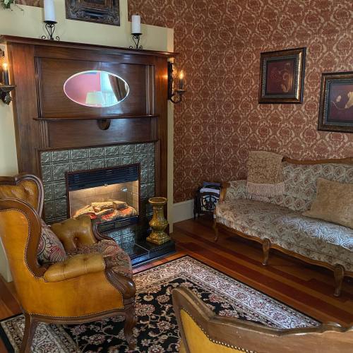 Cozy living room with patterned wallpaper, a fireplace, vintage furniture, and decorative wall art.