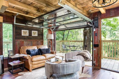 Cozy living space with a leather sofa, glass garage door, and a view of a wooden deck surrounded by trees.