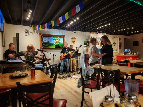 A lively restaurant scene with a band playing music, patrons dancing, and tables set for dining.