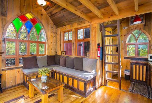 Cozy wooden interior with colorful stained glass windows, a comfortable sofa, and a rustic wooden table.
