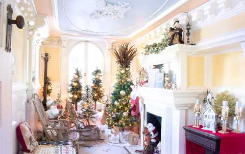 Cozy holiday living room with decorated Christmas trees, festive decor, and a fireplace adorned with seasonal ornaments.