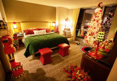 Cozy bedroom decorated for the holidays, featuring a Christmas tree, festive decor, and a green bedspread.